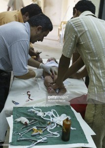Iraqis hold a male child as a doctor circumcises him, July 14, 2005 in Baghdad, Iraq.